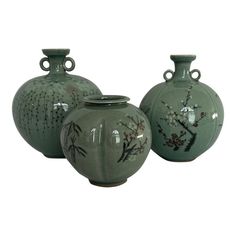 three green vases with designs on them sitting in front of a white background,