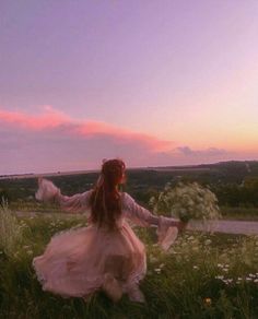 a woman is sitting in the grass with her arms spread out and she is wearing a long white dress