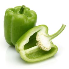 two green peppers cut in half on a white surface with one pepper still attached to the other