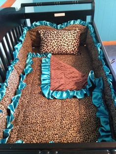 a baby crib with blue ruffles and leopard print sheets on the bed