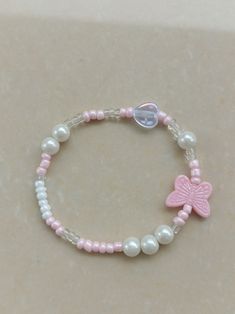 a pink and white beaded bracelet with a butterfly charm on the end of it