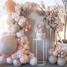 a table topped with balloons and flowers next to a wall