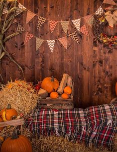 pumpkins and hay bales in front of a wooden wall decorated with bunting