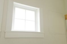 a white bathroom with a window in the corner and no curtains on the wall behind it