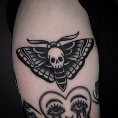 a black and white photo of a skull with a butterfly on it's head