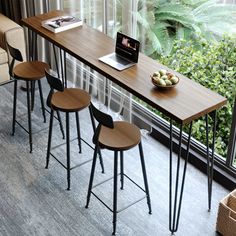 four stools and a table with a laptop on it in front of a window