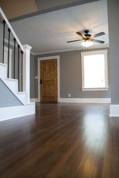 an empty room with hard wood floors and a ceiling fan in the middle of it