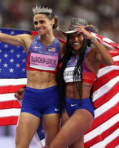 two women standing next to each other in front of an american flag