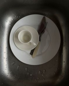 a white plate with a fork and knife on it next to a cup filled with water