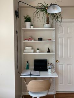 a white desk with a laptop computer on top of it next to a potted plant