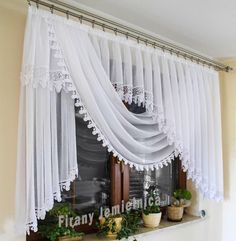 a window with white curtains and potted plants