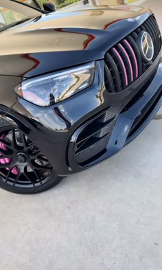 the front end of a black car with pink stripes and chrome rims on it