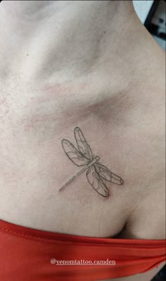 a woman's chest with a dragonfly tattoo on her left side ribcage