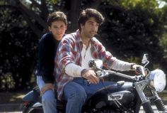 two young men riding on the back of a motorcycle