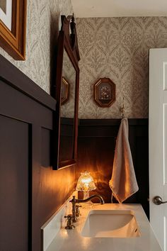 a white sink sitting under a bathroom mirror next to a wooden framed wall mounted clock