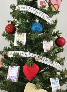 a small christmas tree decorated with ornaments and cards for the children's names on it