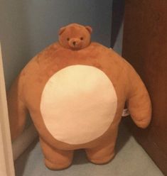 a large brown teddy bear sitting on top of a toilet