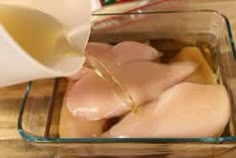 a glass container filled with chicken breast and milk being poured on top of the meat