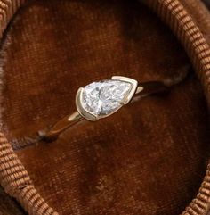 a diamond ring sitting on top of a brown velvet bag