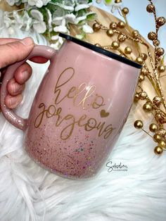 someone is holding a pink coffee mug with gold glitters on it and the words hello gorgeous written in cursive writing