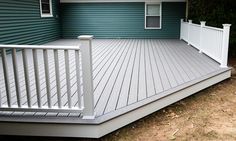 a deck with white railing and blue siding