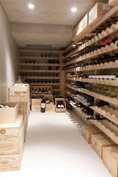 a wine cellar filled with lots of bottles and wooden crates on the floor, along with shelves full of empty wine bottles