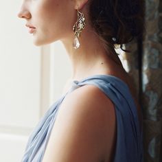 a woman in a blue dress looking off into the distance with earrings on her head