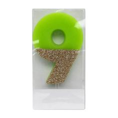 a green plastic object with gold glitter in the shape of a number 7 on it's side