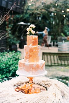 a three tiered cake sitting on top of a glass table covered in white fur