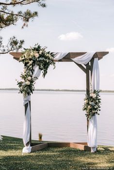 an outdoor wedding setup with white draping and greenery on the arbors