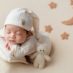 a baby is sleeping next to a teddy bear on a bed with stars and moon decorations