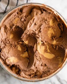 a bowl filled with chocolate ice cream sitting on top of a marble counter next to a towel