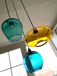 three different colored glass pendants hanging from a ceiling