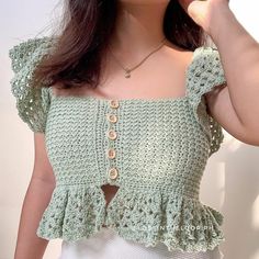 a woman wearing a green crochet top and white skirt