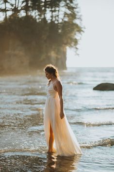 a woman in a white dress standing on the beach