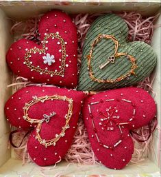 four red hearts are in a box with some gold chains and other jewelry on them