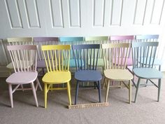 six different colored wooden chairs sitting in a row next to each other on the floor