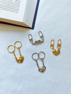 four pairs of gold and silver metal keychains sitting next to an open book