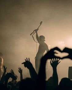 a person on stage with their arms in the air and hands raised up as they perform