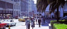 people are walking down the street in front of cars