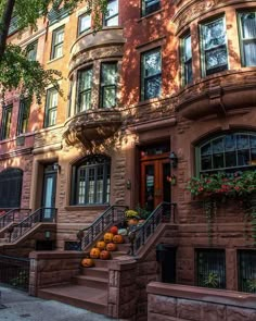 an old brick building with many windows and steps leading up to the front door, surrounded by greenery