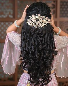 the back of a woman's head with long hair and flowers in her hair