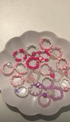 a white plate topped with lots of pink and purple bracelets on top of it