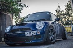 a small blue car parked in front of a fence