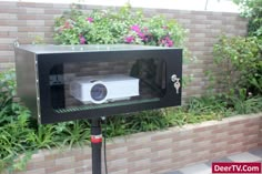 a small projector sitting on top of a black stand in front of a brick wall