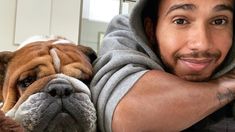 a man laying on the floor next to a brown and white dog wearing a hoodie