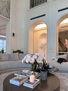 a living room filled with lots of furniture and flowers on top of a coffee table