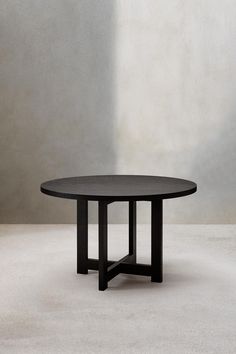 a black table sitting on top of a white floor next to a gray wall and chair