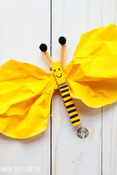 a yellow butterfly made out of paper on top of a white wooden table with the words,