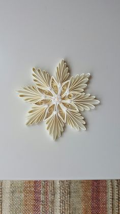 a white paper snowflake sitting on top of a table next to a rug